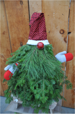 Evergreen tree cuttings are made to look like a gnome by being bunched together to make a triangle with a red and black pointed hat, a red bell as a nose, and mittens on each side.